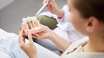 a dentist showing a patient a model of a dental implant